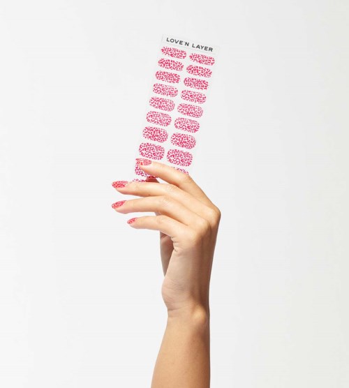 A hand holds a transparent sheet with text about a love layer product, featuring a pink-patterned design.