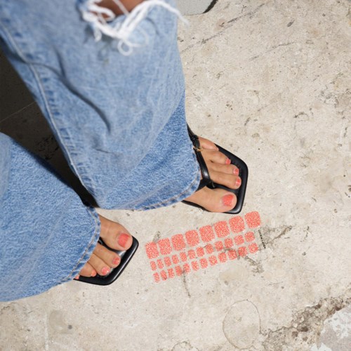 Feet in sandals and jeans near a red marking on a concrete floor.