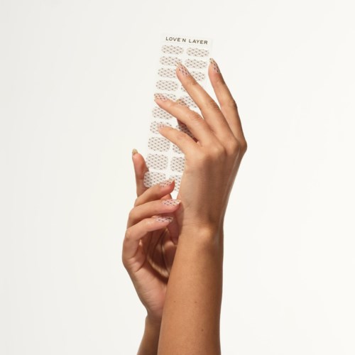 A hand holds a transparent nail sticker sheet labeled "LOVEN LAYER" on a white background.