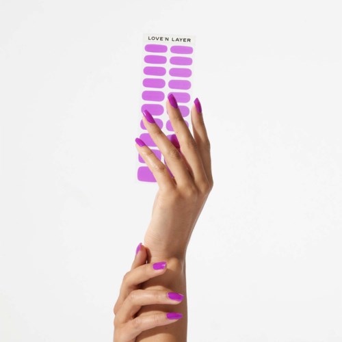 A hand with purple nail polish holds a sheet of purple stickers labeled "LOVE N LAYER."