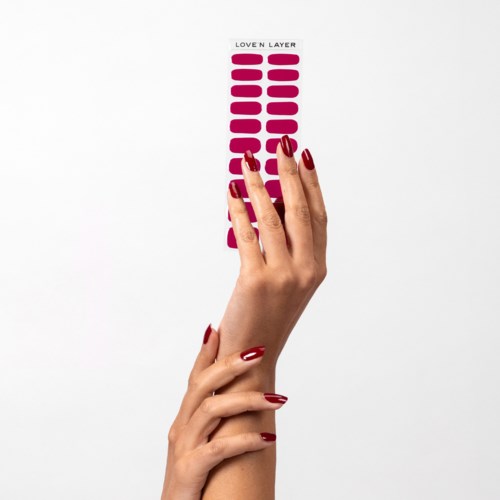 A hand with red nails holds a strip of pink lipstick colors labeled "Loven Layer."
