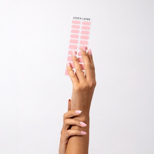 A hand holds a sheet with pink labels labeled "LOVE'N LAYER" on. The sheet has multiple empty pink spaces.