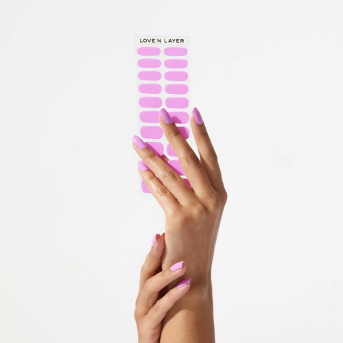 En hand med rosa naglar pekar på ett klistermärkesark med texten "LOVE N LAYER".