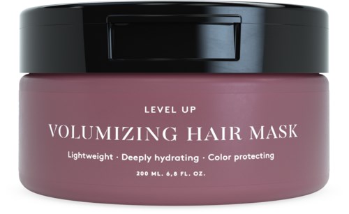 Ein rosa Behälter mit schwarzem Deckel, beschriftet 'Volumizing Hair Mask' für Haarpflege. Es ist leicht, feuchtigkeitsspendend und farbschützend.