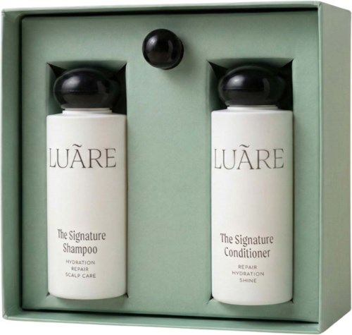 Zwei Haarpflegeflaschen, Shampoo und Conditioner, in einem grünen Karton mit einer kleinen schwarzen Kugel.