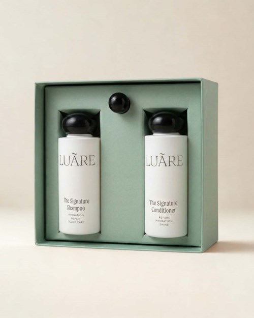 Satz aus zwei weißen Flaschen mit schwarzen Deckeln, beschriftet Shampoo und Conditioner in einer grünen Schachtel.