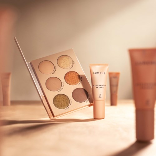 Een oogschaduwpalette met zes kleuren en een tube met Lumene Eyeshadow Primer op een houten oppervlak.