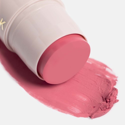 Een roze lippenstift ligt met zijn kleur uitgesmeerd op een witte ondergrond.