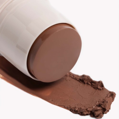 Eine weiße Tube gibt braune Creme oder Lippenstift auf eine Oberfläche.