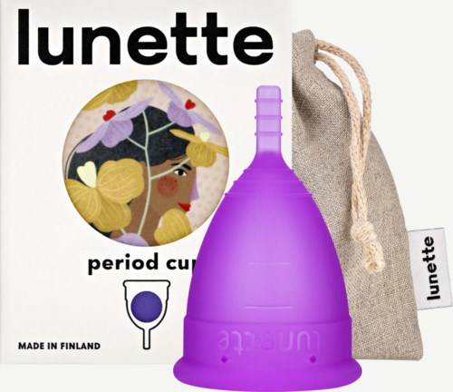 Eine lila Menstruationstasse mit Stoffbeutel, Verpackung zeigt eine Frau mit Brille und blondem Haar. Hergestellt in Finnland.