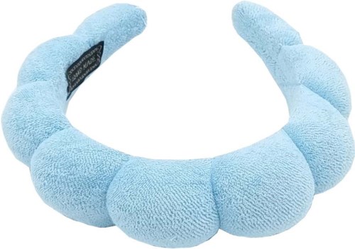 A soft, plush, light blue neck pillow with a black label on one side.
