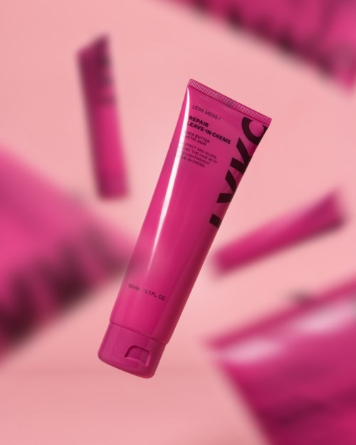 Roze tube met huidverzorgingsproduct staat rechtop, met wazige vergelijkbare items op de achtergrond.