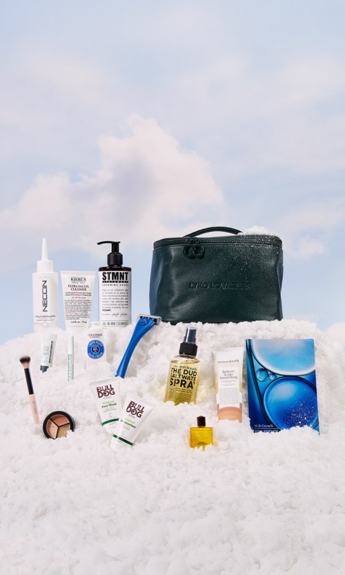 Eine Anordnung von Hautpflege- und Kosmetikprodukten auf Schnee, inklusive Cremes, Spray, Werkzeugen und einer blauen Tasche.