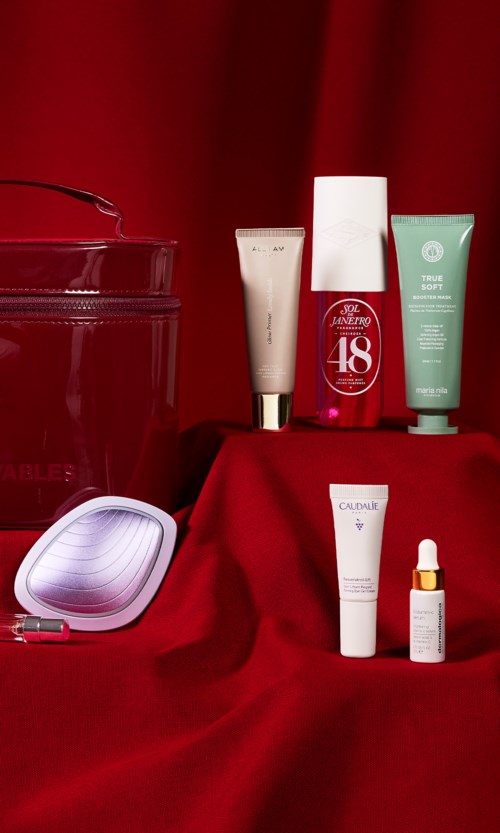 Sammlung von Hautpflege- und Make-up-Produkten mit rotem Hintergrund, inklusive Cremes, Tuben und Tropfflasche.
