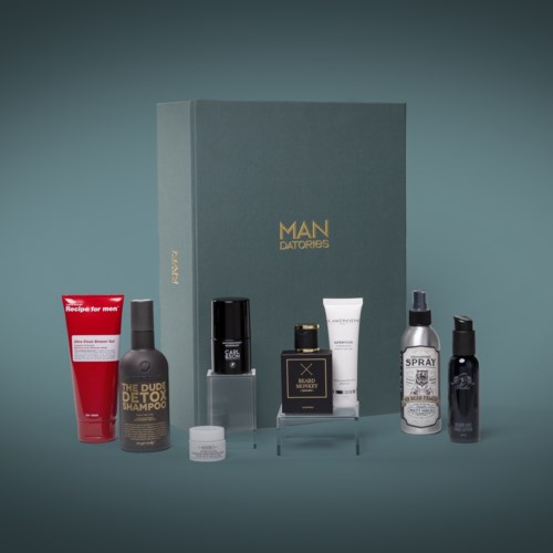Ett presentset med olika groomingprodukter, inklusive schampo, spray, kräm och parfym, framför ett box.
