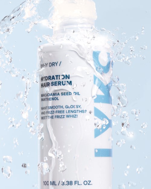Een waterspatting raakt een fles haarserum met blauwe en witte verpakking, met tekst die de kenmerken beschrijft.