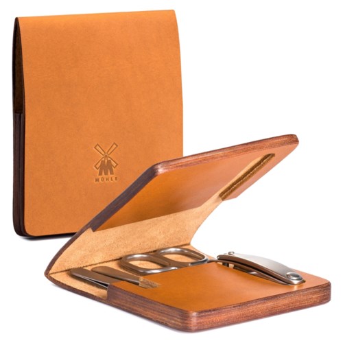A leather key holder inside a wooden case with scissors, key, and a small tool, all placed on a wooden surface.