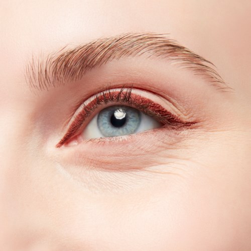 A close-up of a blue eye with clear skin, long eyelashes, and light eyebrows.