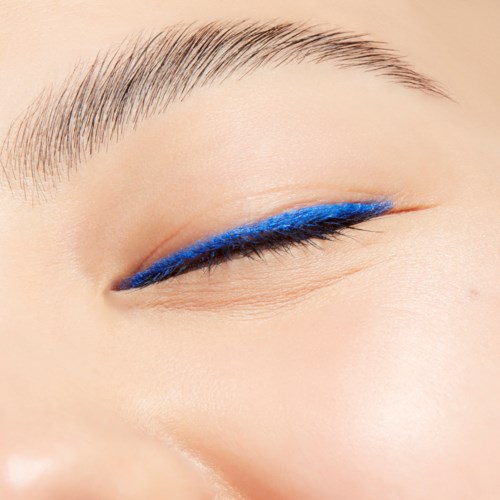 An eye with blue eyeliner and well-groomed eyebrow, close-up of makeup on eyelid.