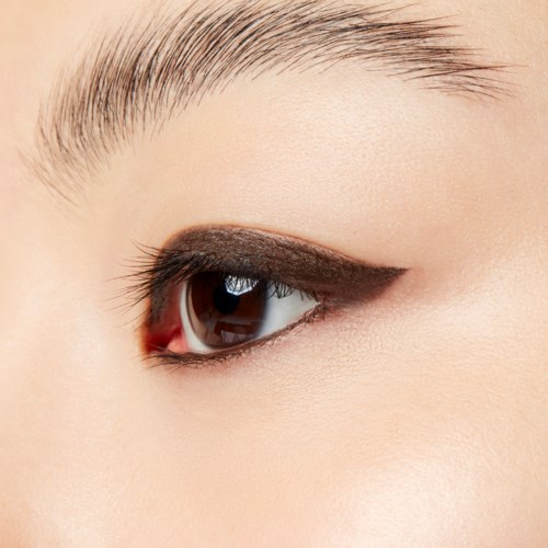 Close-up of a person's eye with dark eyeshadow and neatly groomed eyebrow.