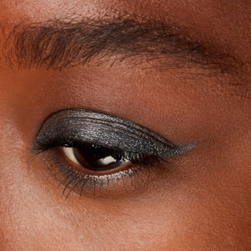 Close-up of a person's eye with silver and black eye makeup, focusing on the eyelid and eyebrow.
