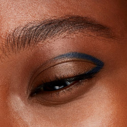 Close-up of a person’s eye with eye makeup and blue eyeliner on the eyelid.