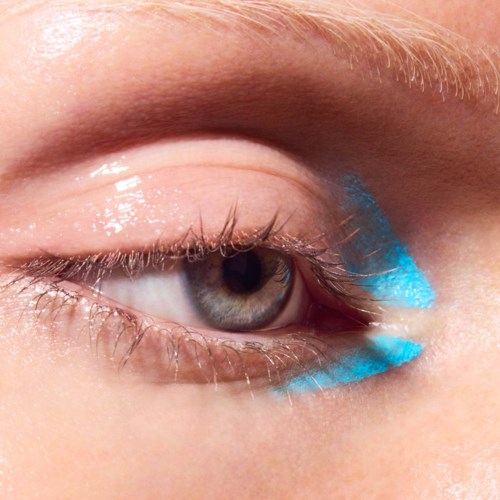 Close-up of a human eye with a streak of bright blue eyeshadow beneath it.