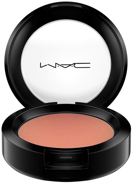 A round makeup compact with a mirror, containing peach-colored powder from MAC Cosmetics.