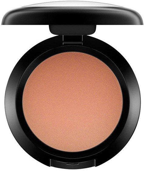 A round makeup compact with beige powder inside and a black lid.