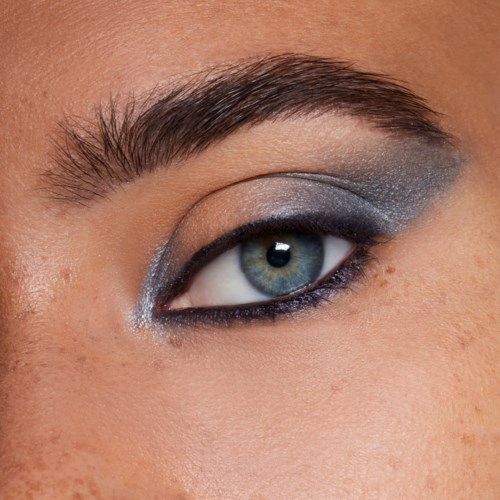 Close-up van een vrouw haar oog met gedetailleerde grijze en zwarte oogmake-up en goed gedefinieerde wenkbrauw.