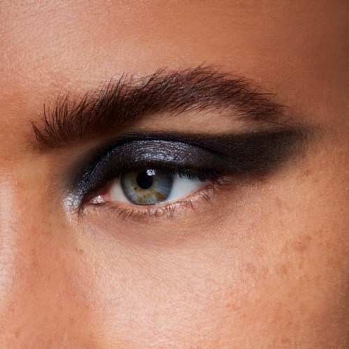 Nahaufnahme eines Auges mit dunklem Augen-Make-up und braunen Augenbrauen. Die Haut sieht glatt und klar aus.