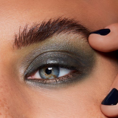 Närbild på ett persons öga med mörk ögonsmink, inklusive ögonskugga och eyeliner, och välskött ögonbryn.
