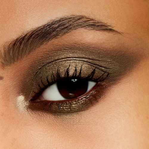Närbild av ett öga med smink, inklusive eyeshadow, eyeliner och mascara. Ögonbrynet är välformat.