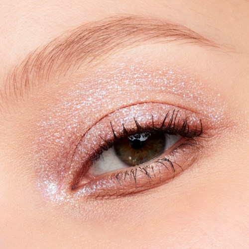 Ett öga med glittermakeup och långa ögonfransar, nära bild som visar detaljerad ögonlock och hud.