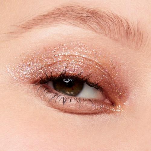 Närbild av ett öga med glittermakeup på ögonlocket och nedre fransraden.