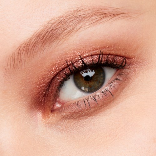 Närbild av ett brunt öga med ögonmakeup och långa fransar.