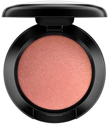 A round makeup compact with pinkish blush inside and a black lid.
