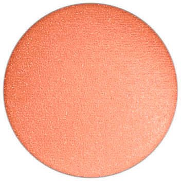 A round makeup blush in a peachy-orange shade with a smooth, matte surface.