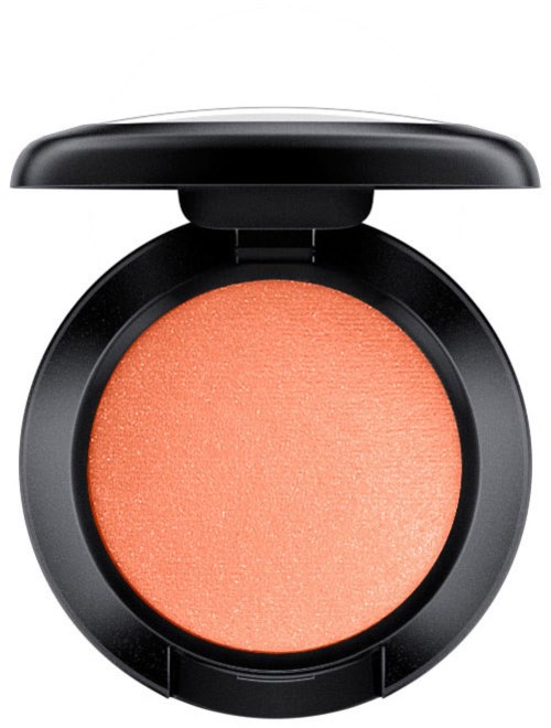 A round makeup blush in a black compact with a lid. The blush is peach-colored with a shimmery finish.