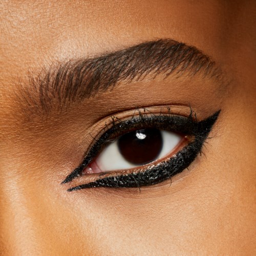 Close-up van een vrouwelijk oog met dikke zwarte eyeliner en verzorgde wenkbrauwen.