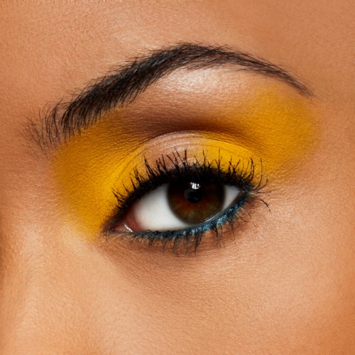 Close-up of an eye with yellow eyeshadow, black eyeliner, and long eyelashes.
