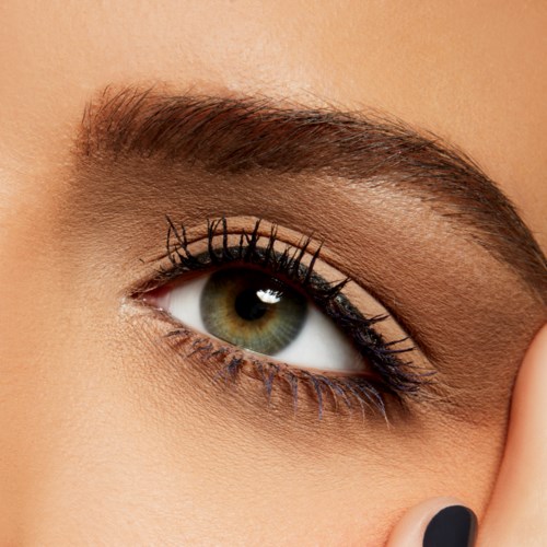 A close-up of a person's eye with well-defined eyebrows, eye makeup, and long eyelashes.