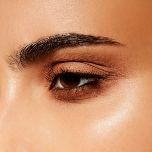 Close-up of a woman's eye with makeup, showing eyelashes, eyebrow, and brown iris.