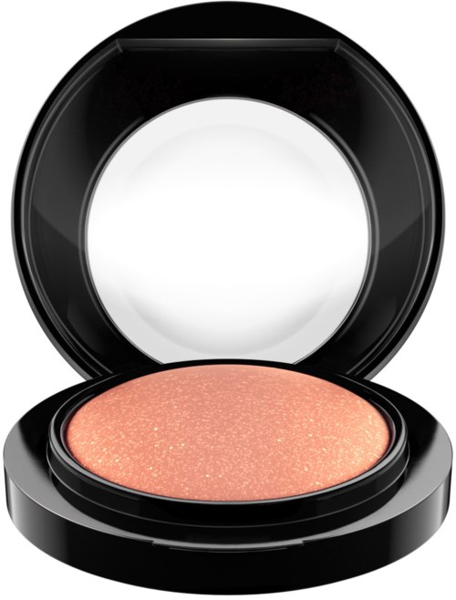 A round, peach-colored makeup item with shimmer inside a black compact case.