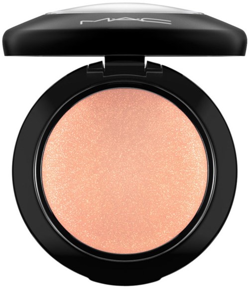 A round makeup compact with a peach-colored shimmery powder inside and a black lid with brand letters.