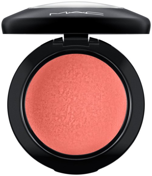 A round blush compact with a coral-colored powder and black lid, displaying the word MAC.