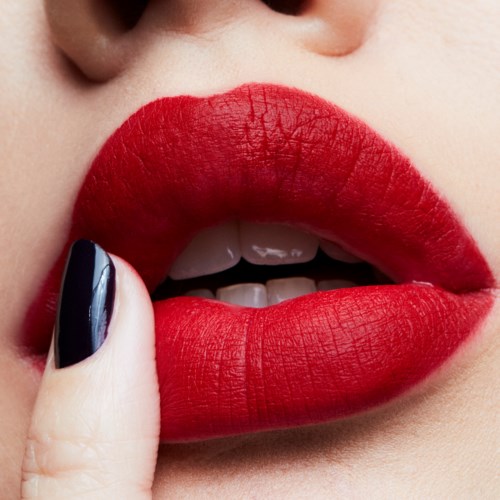 Close-up of lips with red lipstick, finger near lips, skin visible around lips.