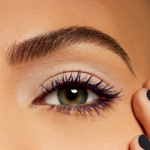 A close-up of a woman's eye with makeup, including blue mascara on upper and lower lashes, and well-groomed eyebrow.