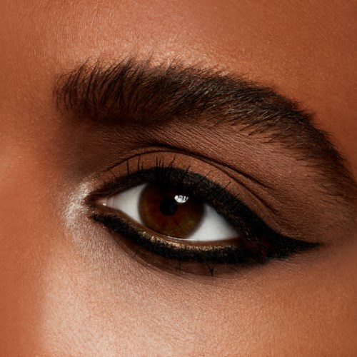 Close-up van een persoon met oogmake-up, inclusief zwarte eyeliner, bruine ogen, wenkbrauw en huiddetails.