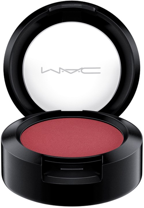 A round black compact with M·A·C logo inside, containing pinkish-red face makeup.